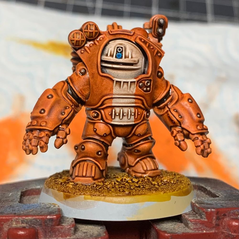 Squat exo-kyn miniature, painted orange. With a white helmet and a white strip on their chest.