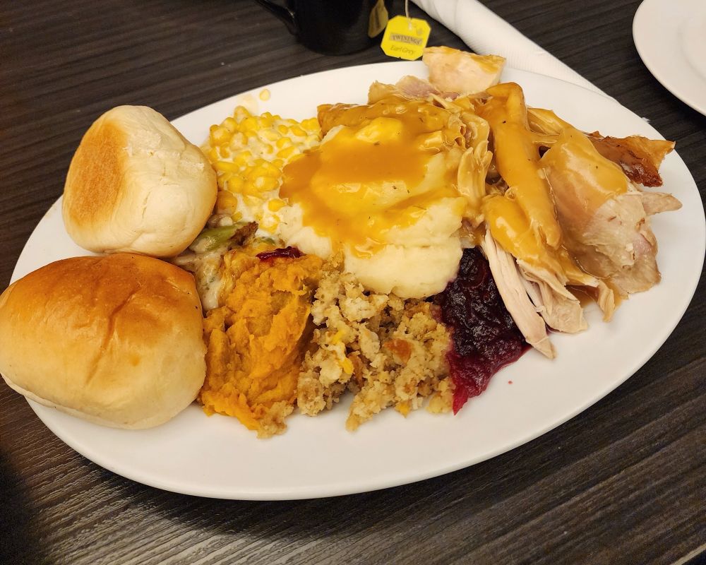 A plate of Thanksgiving dinner from Uptowner American Diner in Taichung, Taiwan. The plate includes all standard American Thanksgiving dinner items, Turkey and Mashed Potatoes with gravy, creamed corn, green bean casserole, sweet potato hot dish, stuffing, cranberry sauce and dinner rolls.