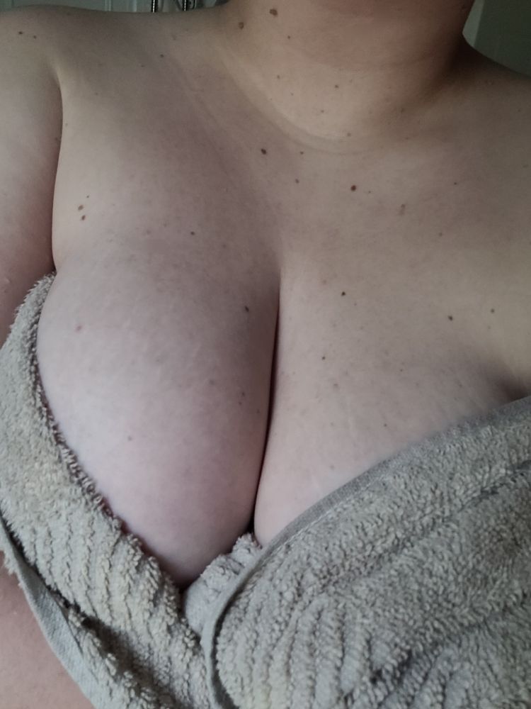 A full, pale chest dotted with freckles and stretch marks, wrapped in a grey towel.