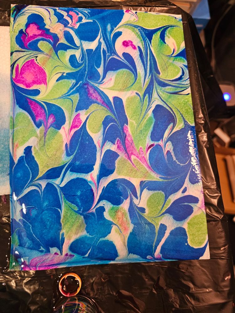 A water marbled print with large swirls of bright blue, bright green and hot pink. There is white space between the large petal like shapes.