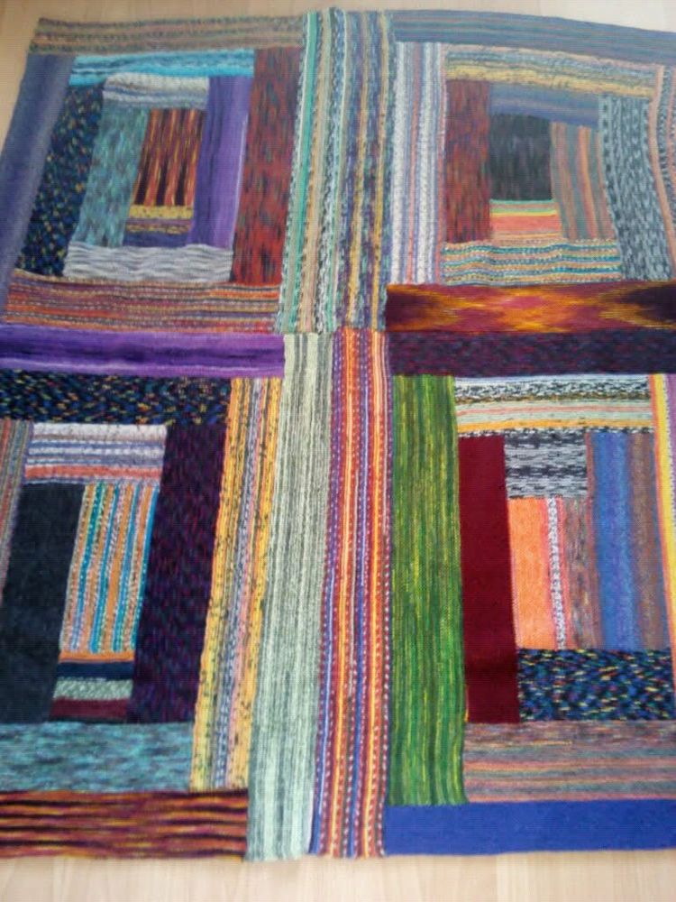 Knitted blanket made from a variety of colours of variegated sock yarn. 4 panels sewn together. Each panel is log cabin design with each section in different yarn.