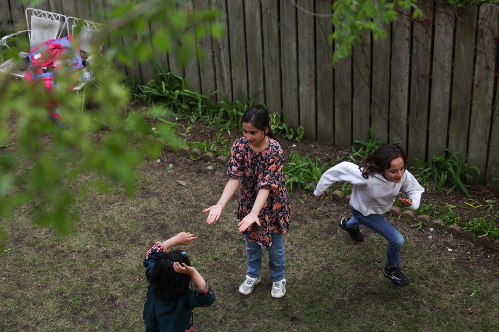 Razma Azizi, 12, center, plays with a neighbor child as her sister, Zhra, 10, runs past in a courtyard outside their new home in the West Ridge neighborhood Friday, May 2, 2025, in Chicago.