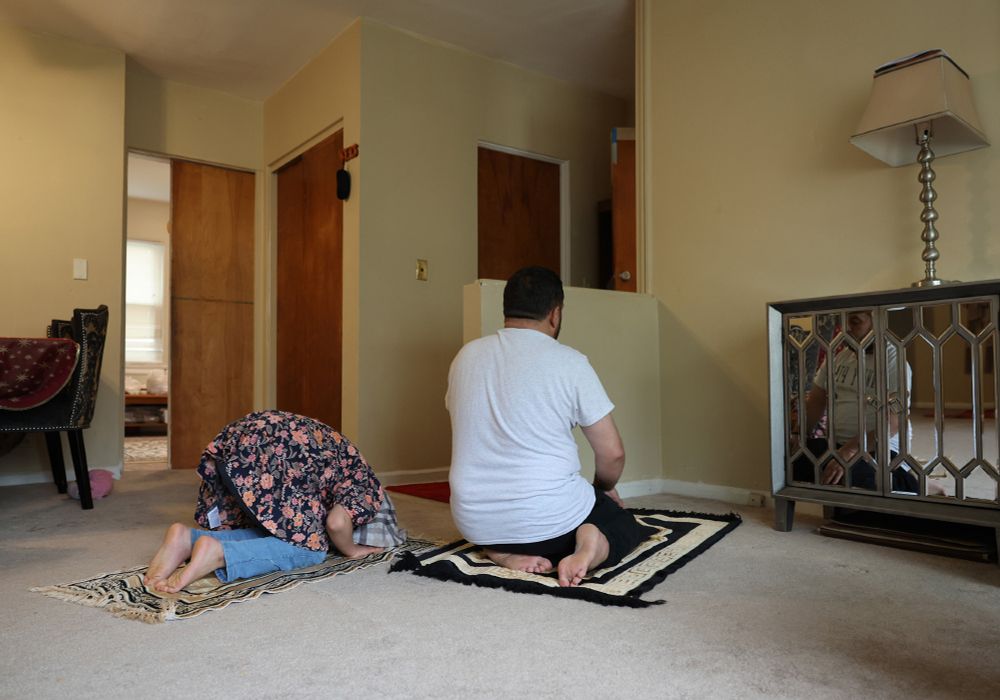 Razma Azizi, 12, prays alongside her father, Hamid, in the living room of their new home in the West Ridge neighborhood Friday, May 2, 2025, in Chicago. Hamid Azizi helped clear land mines in his native Afghanistan and assisted U.S. military special forces from 2017 until 2021, when the Taliban regained control of the nation. The family fled to Kabul, then Pakistan and Qatar, finally arriving in the U.S. in April. 