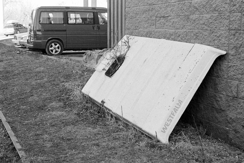 A black and white photo of the top of a Westfalia camper van leaning against the side of a building