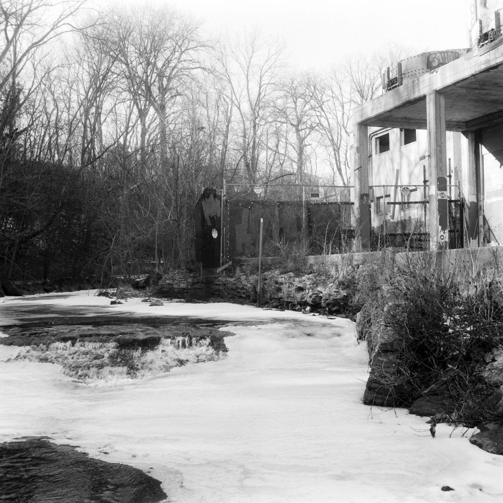 An abandoned grain elevator beside a partially frozen creek