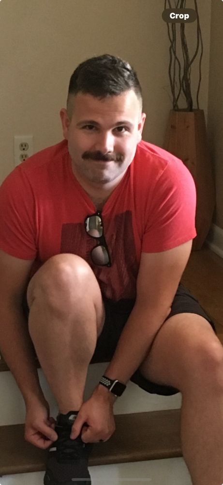 Man with mustache ties his shoe 
