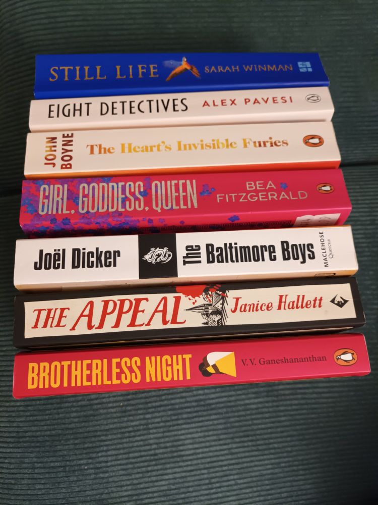 A pile of 7 of the 8 books against a sea green background.
Brotherless Night by V.V Ganeshananthan 
The Appeal by Janice Hallett
The Baltimore Boys by Joel Dicker
Girl. Goddess. Queen by Bea Fitzgerald
The Heart's Invisible Furies by John Boyne
Eight Detectives by Alex Pavesi
Still Life by Sarah Winman