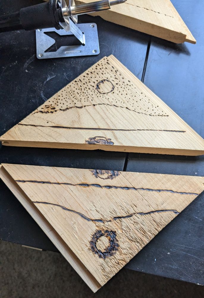 Two pieces of wood. The top triangle has what is supposed to be a moon, stars, mountain, and a reflection in a lake, the bottom triangle is supposed to be mirrored with the sun. I've done better work in my time.