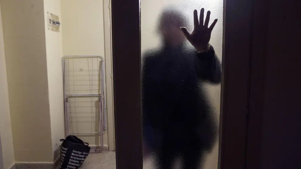 Una víctima de violencia de género oculta su rostro tras una cristalera.