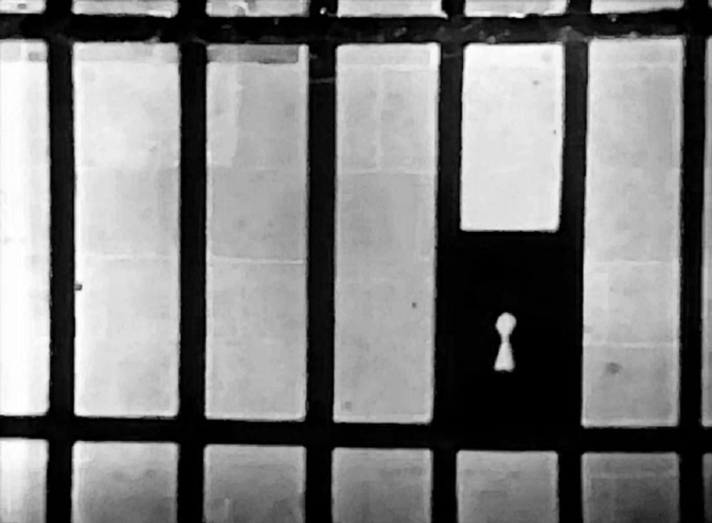 a black and white photo of a jail cell with a keyhole in the middle