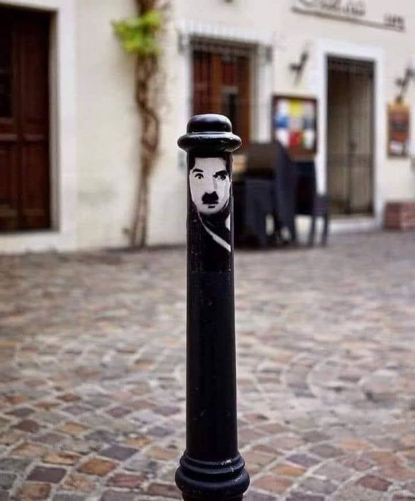 A black bollard with a picture of Charlie Chaplin at the top.
