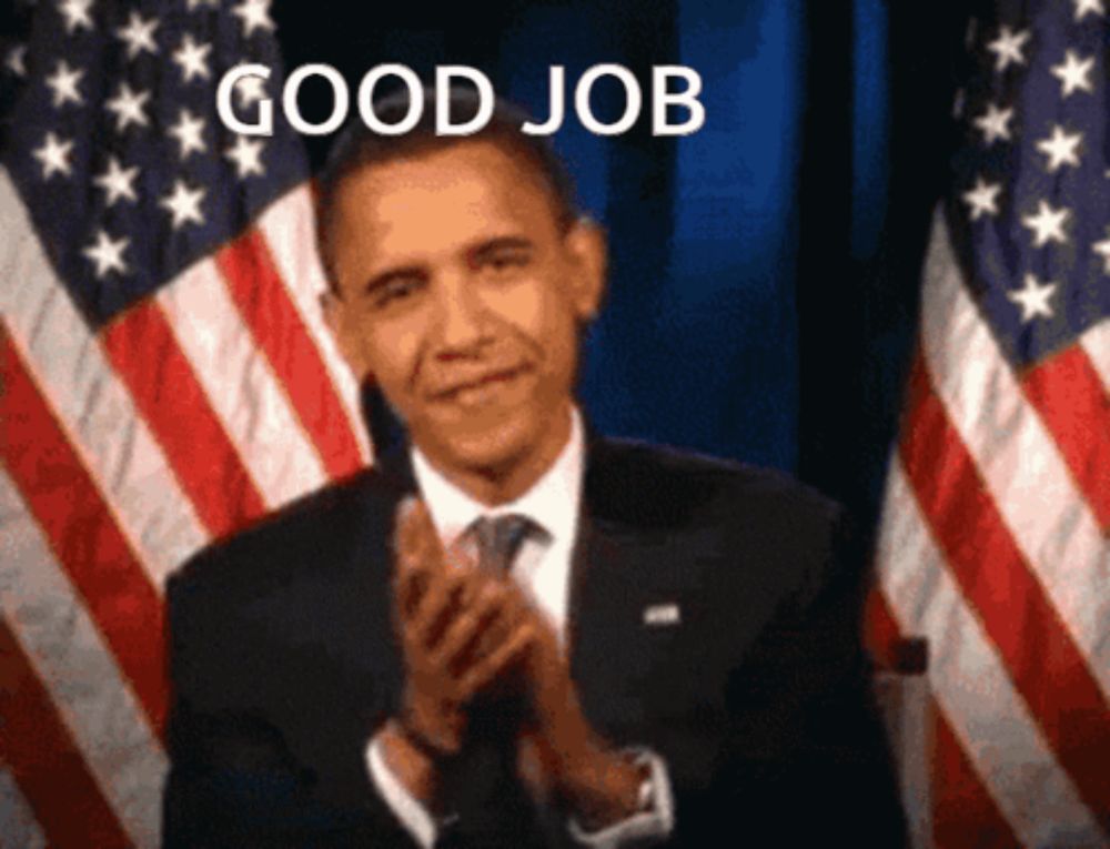 a man in a suit and tie is clapping in front of an american flag with the words good job above him