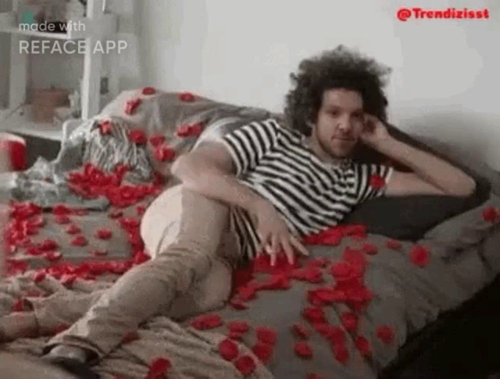 a man is laying on a bed covered in petals of roses .