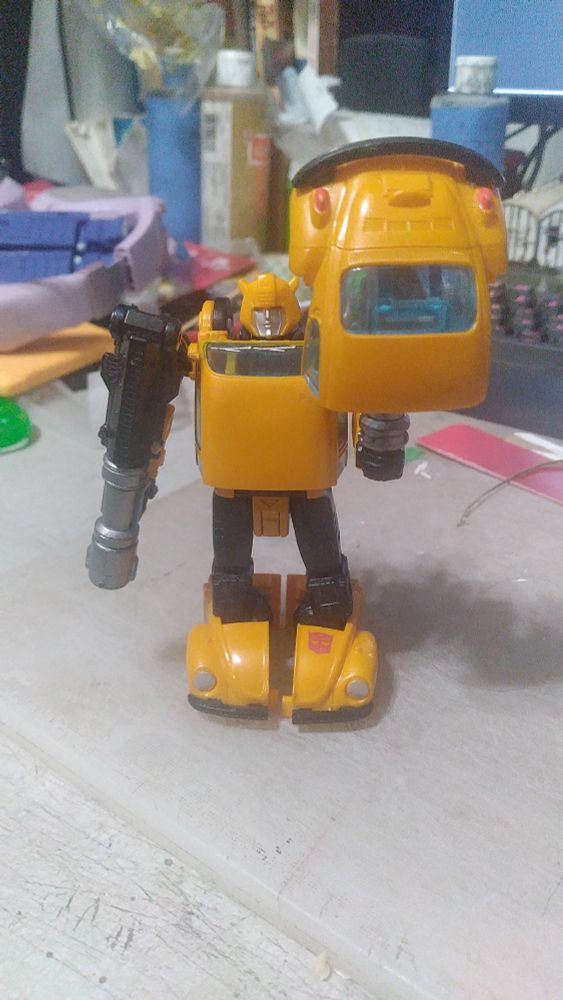 Front view of the Wal-Mart exclusive Cliffjumper-based neo-G1 version of Bumblebee from Transformers, standing in robot mode with one of his guns and the folding black driveshaft/weapon piece assembled into a rocket launcher (held in his right hand, currently pointed at the ground), and the other gun and the rear end of his car mode assembled into a shovel (held upright in his left hand).

This is inspired by the Soldier class from Team Fortress 2, who uses a rocket launcher and a shovel as weapons.