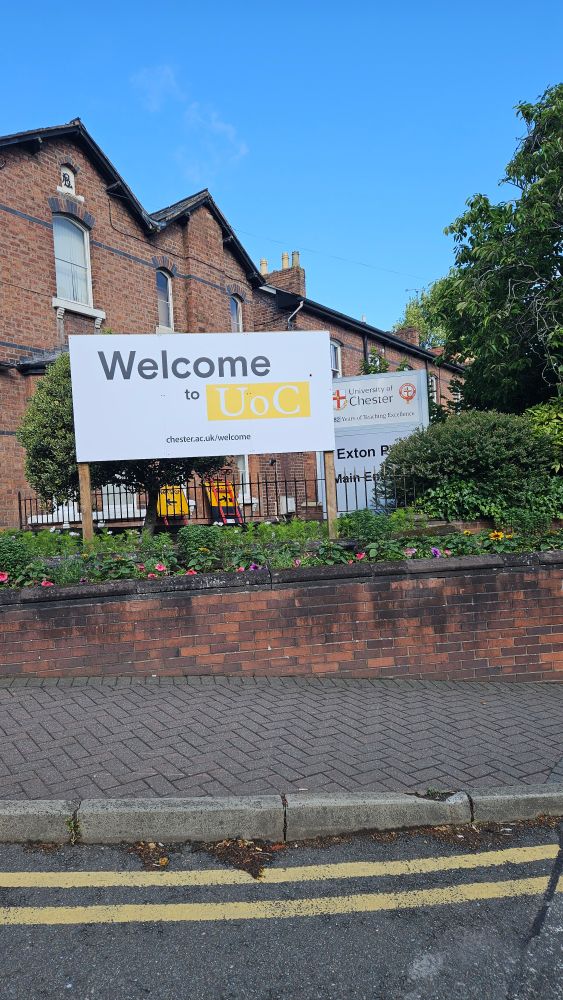 Front entrance to uni of chester. Red brick building with 2 signs saying welcome to UoC and Chester University 