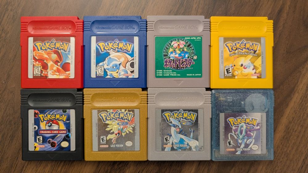 A photograph of the first and second generation pokemon game cartridges for Gameboy. These include Pokemon Red, Blue, Green (Japanese), Yellow, Gold, Silver and Crystal. The cart for Pokemon Trading Card Game is also included.