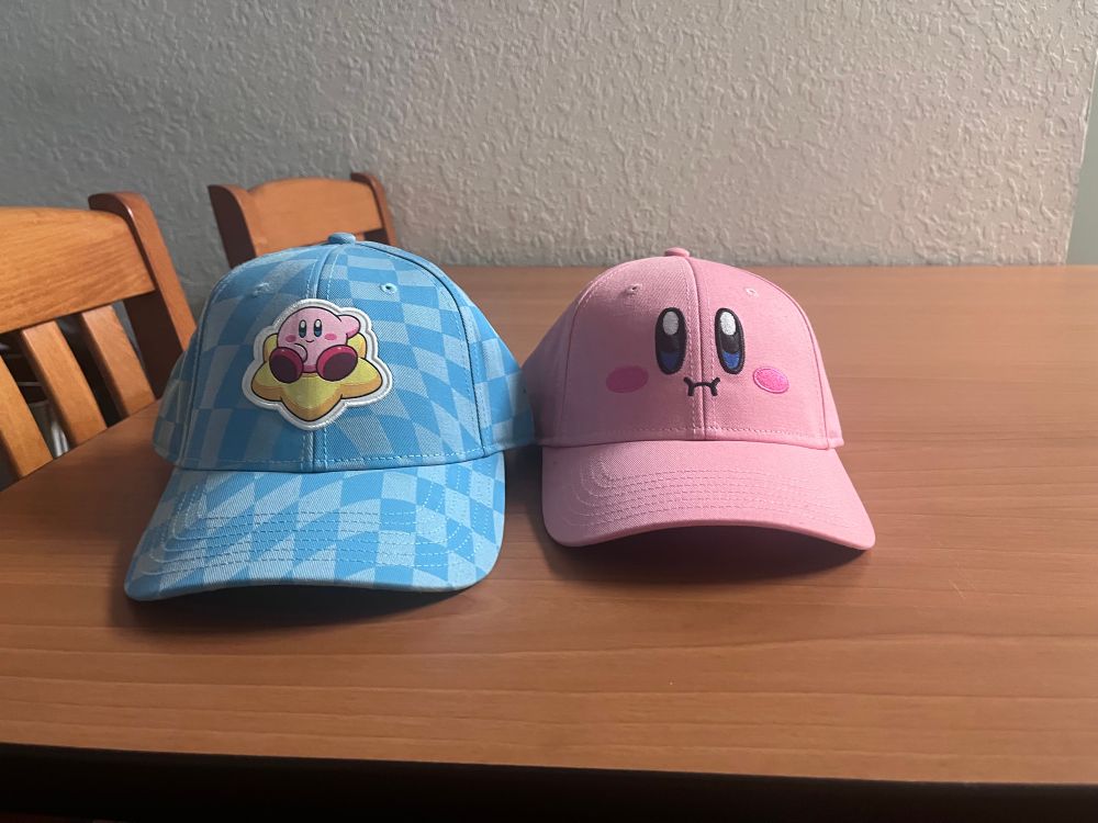 Two Kirby hats. One pink and the other is blue. Both costed way too much
