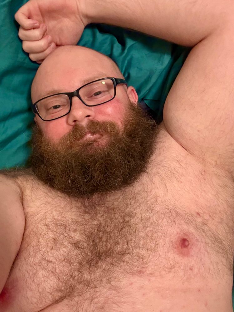 A bearded guy showing off his chest. His nipples hard. 