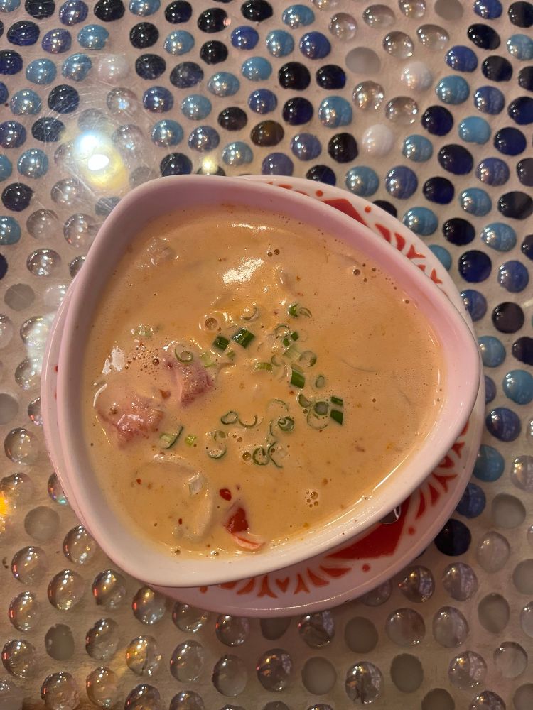 A bowl of tom Kha soup in a triangular bowl 