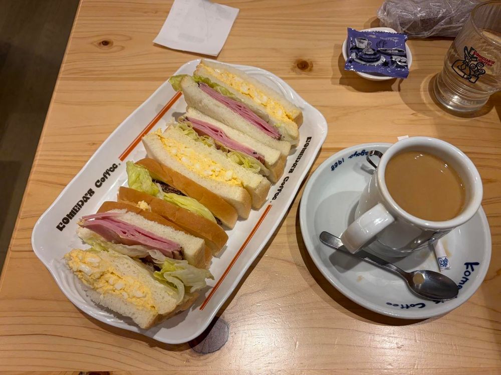 A stack of sandwiches of ham and egg and a cup of coffee