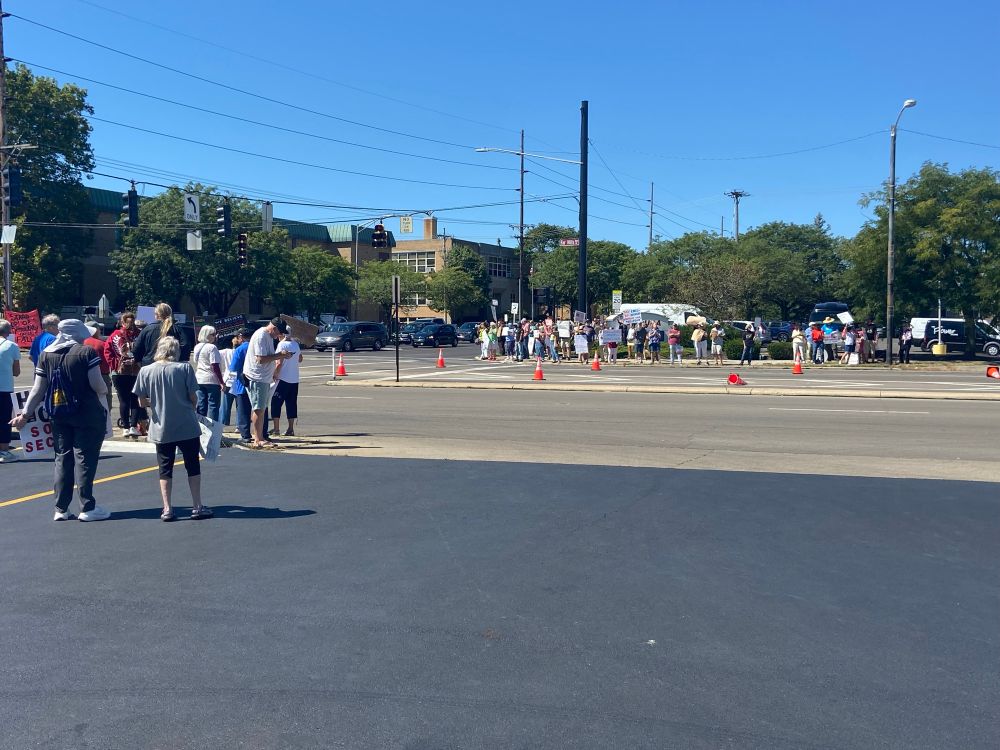 People holding signs to protest Trump and support American workers