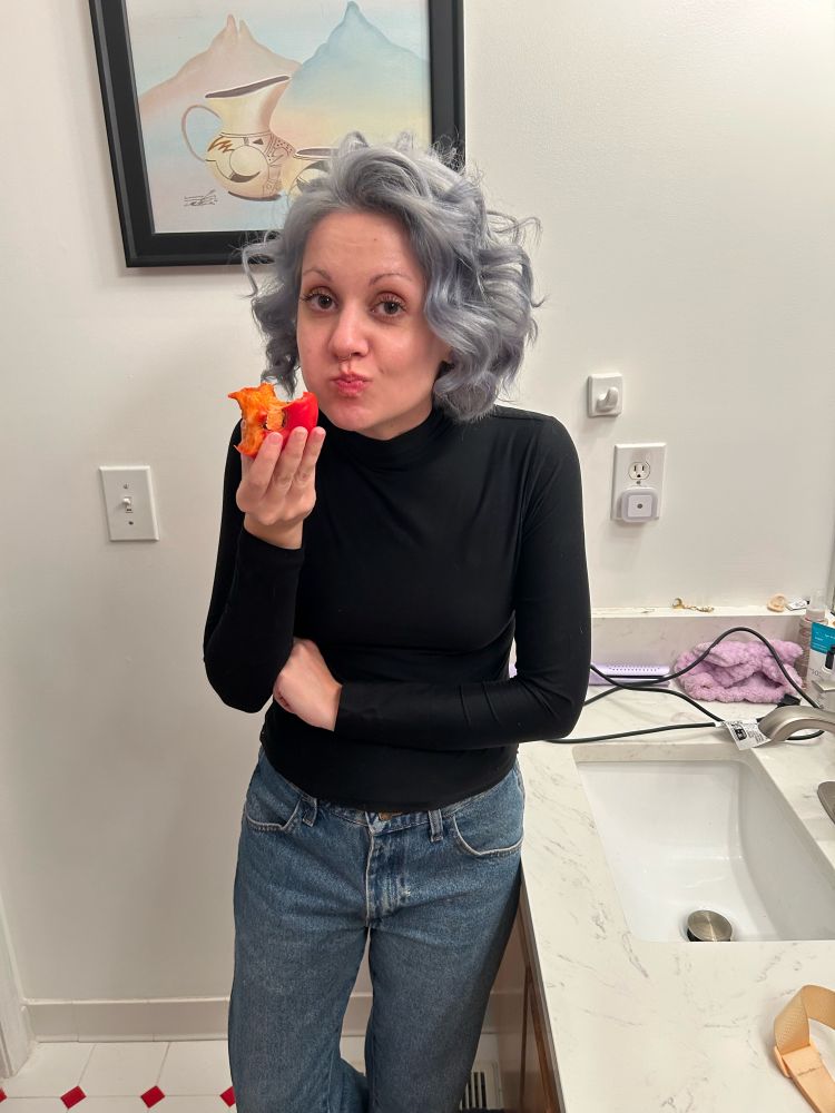 Charis looking at the camera with a cheek full of persimmon and a “caught” expression.