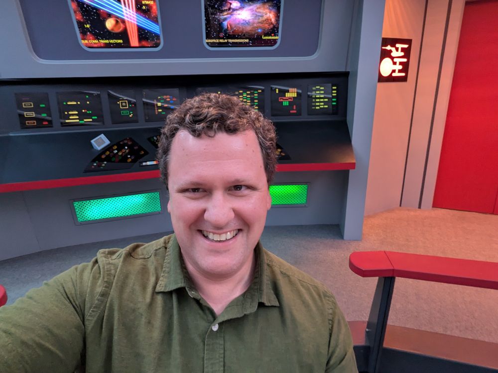 A man in a green shirt (me!) on the bridge of the original Starship Enterprise.