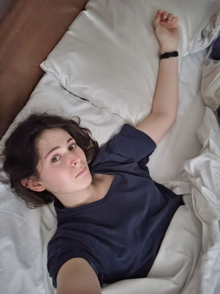 young woman lying in bed, the pillow next to her empty