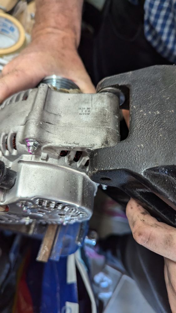Alternator being held whilst a bracket is being tested against it for size. It mostly fits.