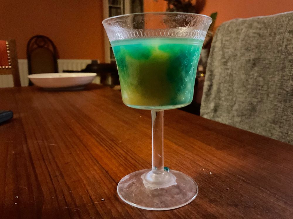Small glass (thankfully) of a swirl of green and yellow alcohol - failed attempt at the Ukrainian flag-in-a-glass must do better hic 