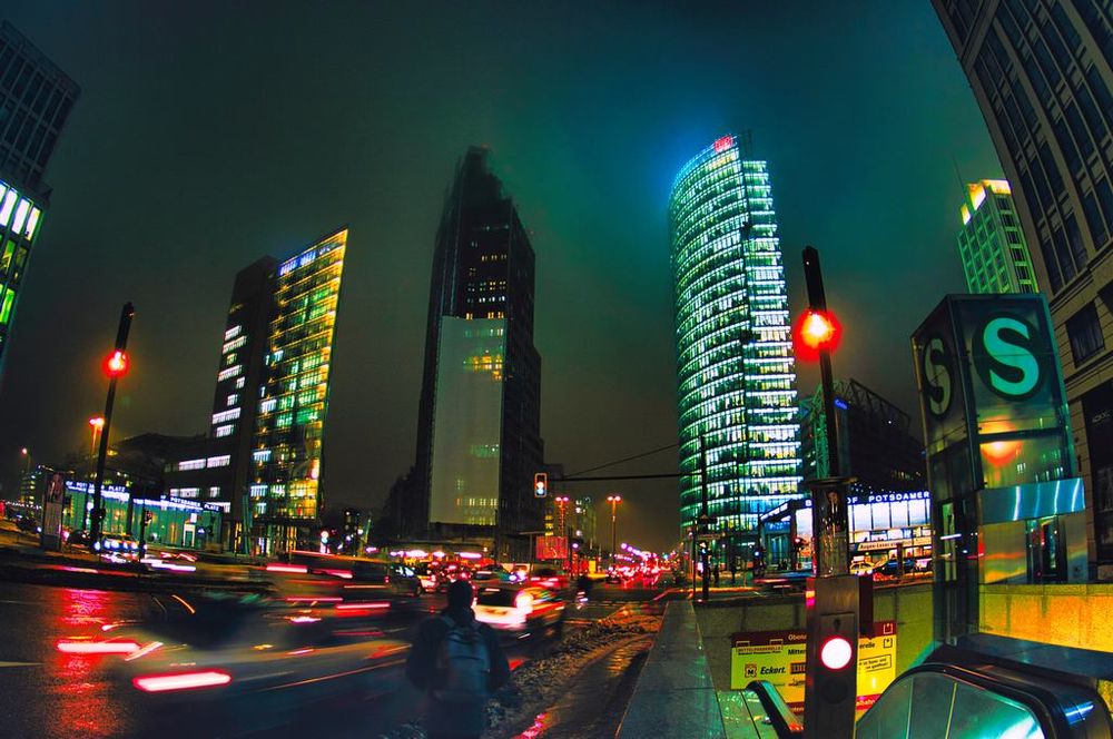 Berlin in einer nebligen Nacht. Die Straßen sind nass, die Lichter der Hochhäuser beleuchten den nebligen Himmel. Schneematsch, kalte Luft. Es ist arschkalt.