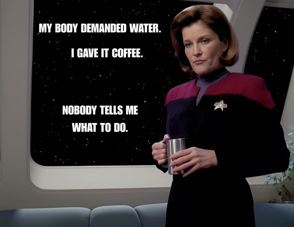 Single panel meme. Captain Janeway is standing and holding a mug of coffee while frowning. Text: My body demanded water. I gave it coffee. Nobody tells me what to do. 