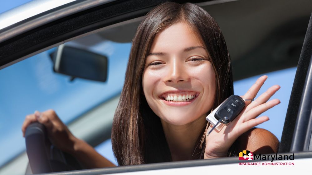 Person sitting in a car holding up a set of car keys through the open window on a sunny day.