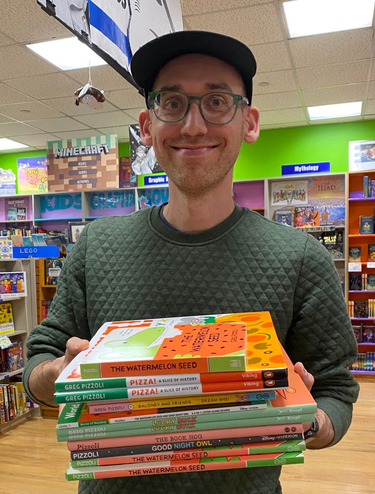 Greg Pizzoli holding a stack of books