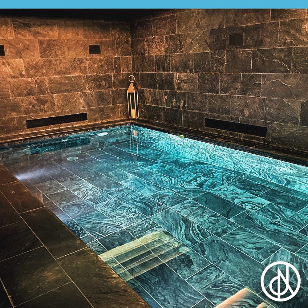 A photo of an indoor swimming pool with floor-to-ceiling tiling on the walls. 