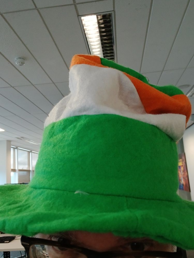 Typ sitzt im Büro mit einem Hut in den Farben Irlands.