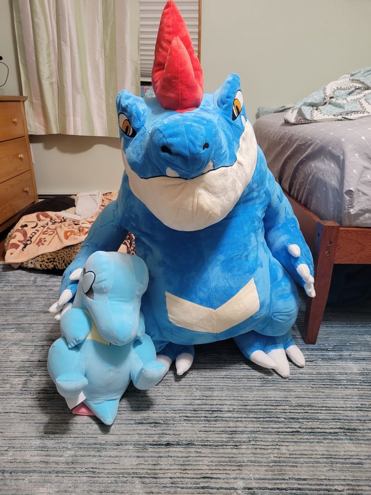 Sleepy totodile and a commissioned feraligatr plush next to each other 