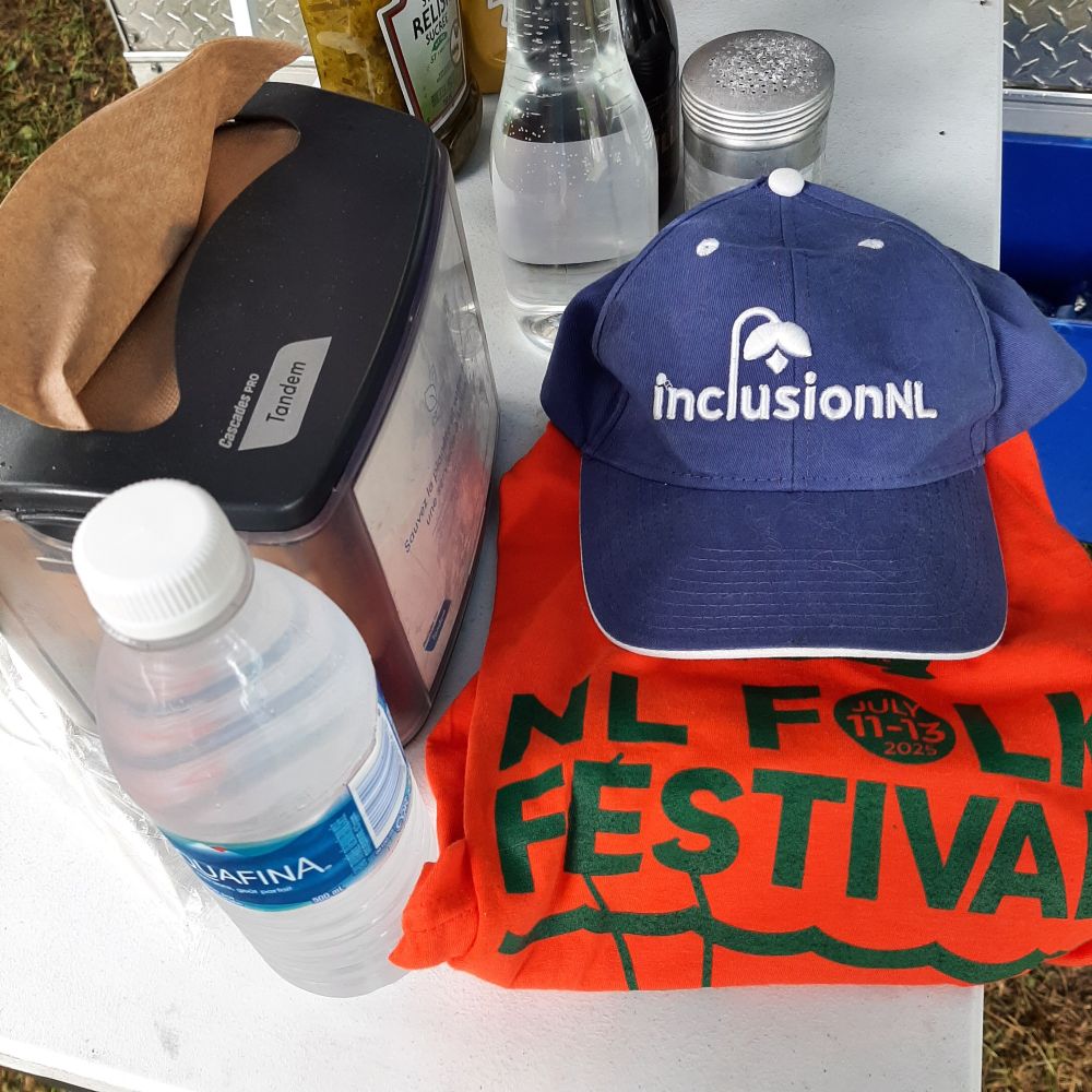 
Image description: a water bottle, an orange tshirt and a periwinkle hat are on a table. Also on the table is a serviette dispenser, a bottle of vinegar, and a salt shaker.