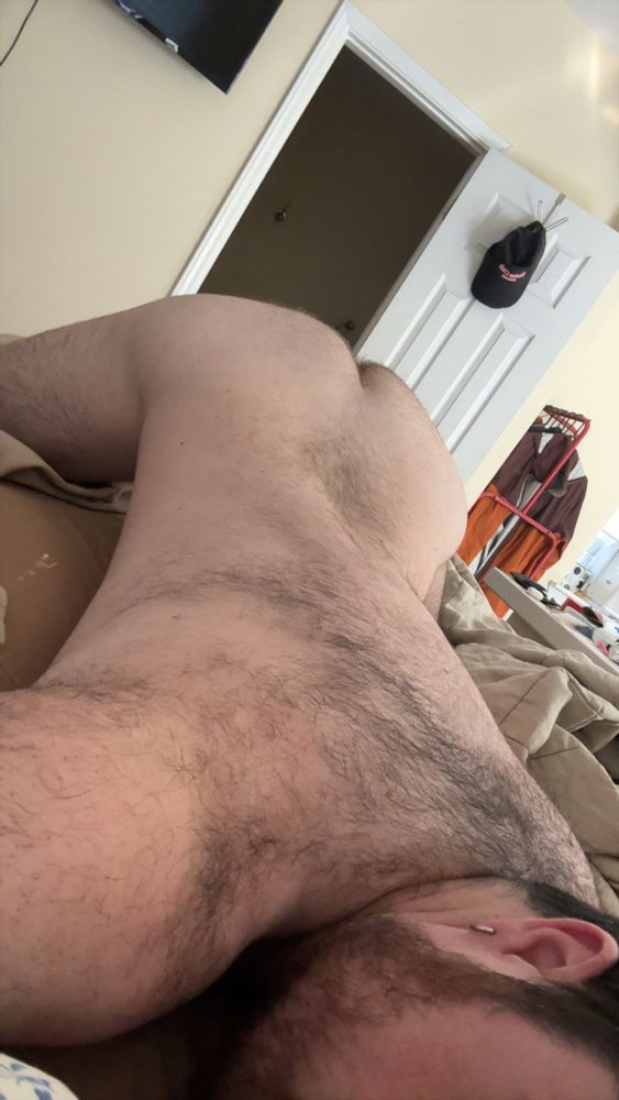 A hairy white boy ass up face down on a bed 