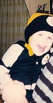 Photo of me at age 2-3 years old, wearing a Steelers hat and jacket and smiling. 