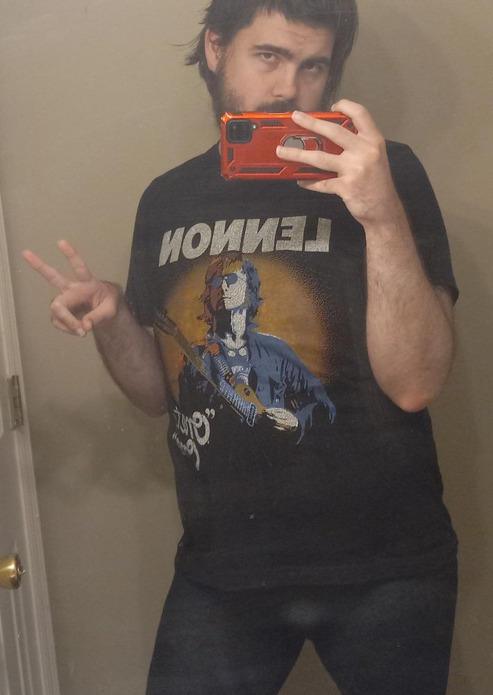 Mona posing in the bathroom mirror in my black John Lennon "One-To-One" T-shirt, my Grey (it says denim but they a darkish grey) leggings, holding my phone sideways, with a Peace sign.