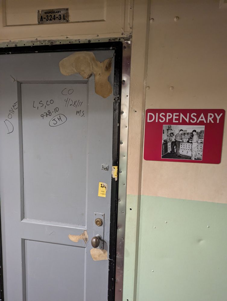 Door with a sign that says 'Dispensary' aboard a WWII battleship