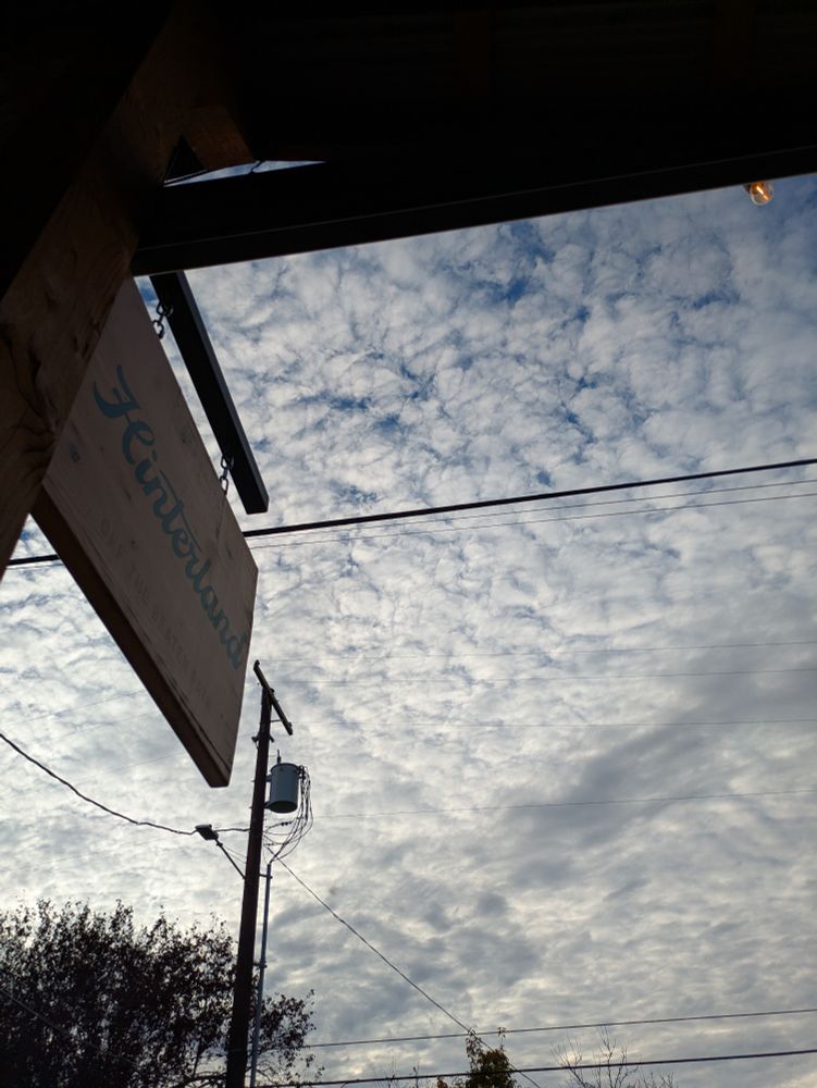 Light clouds over the Hinterland sign with a powerpole. 