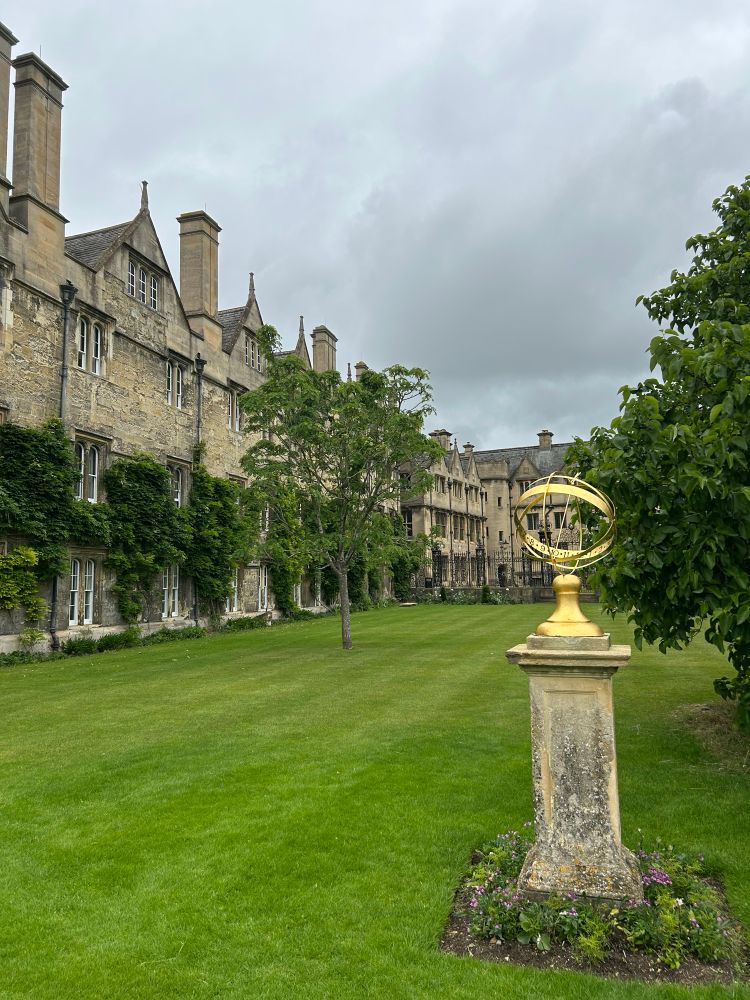 Picture of an open courtyard with gold sculpture on stone pedestal.