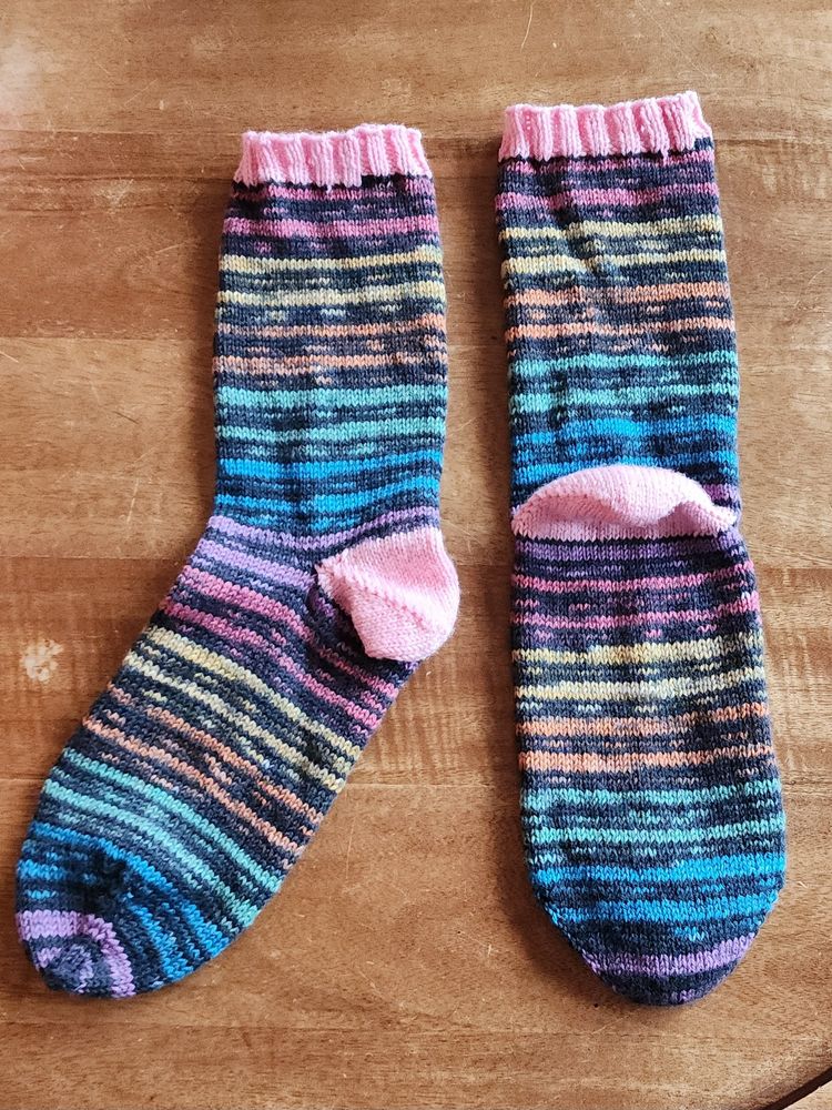 A pair of rainbow socks with pink heels and cuffs.
