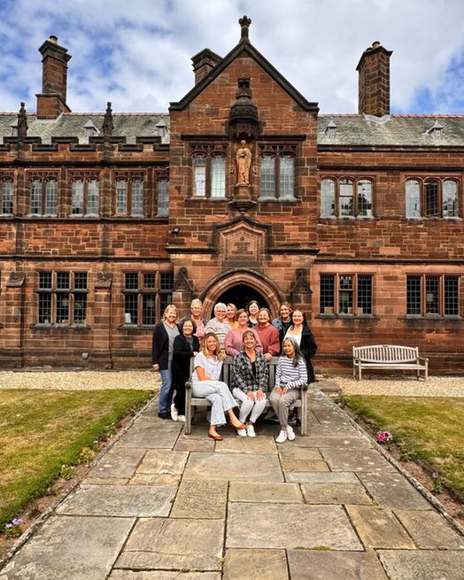 A group of friends sit on a bench outside the Gladstone's Library building.