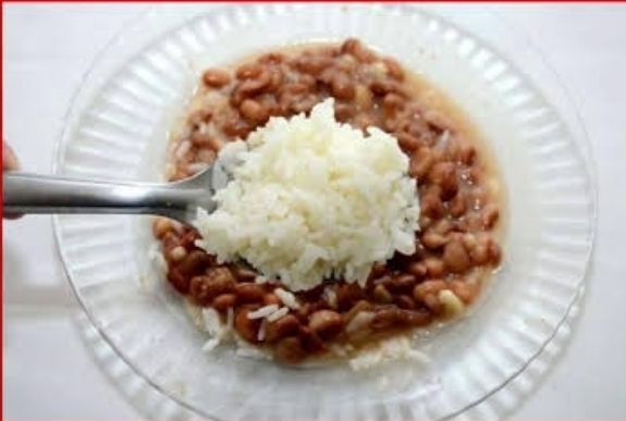 um prato com o feijão por debaixo do arroz.