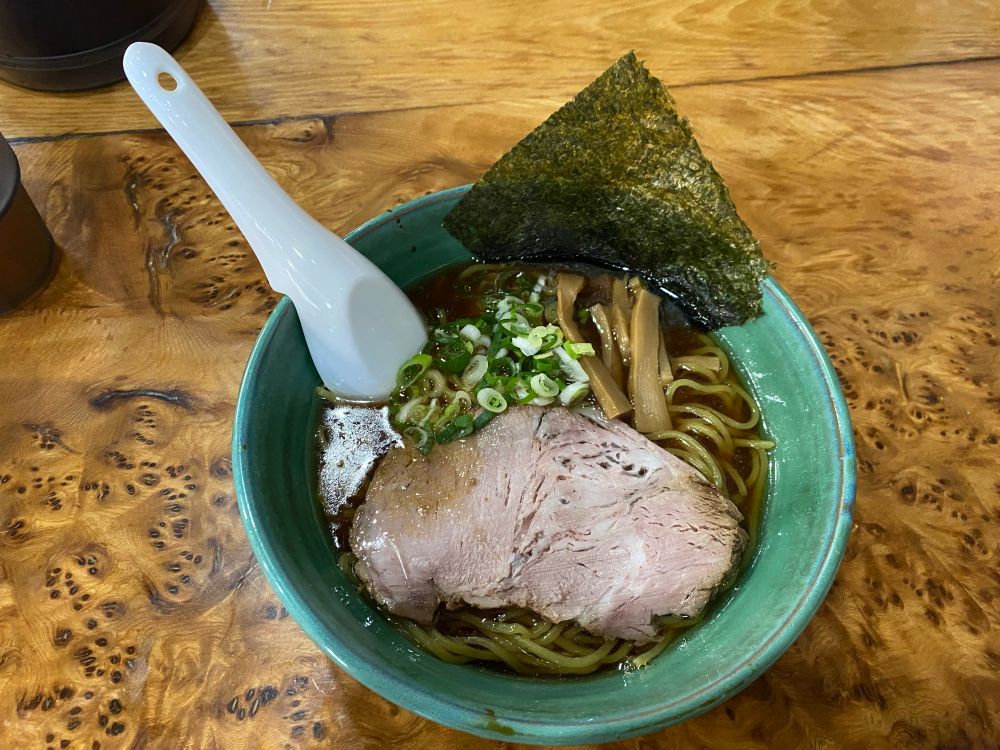 緑色の器に入った醤油ラーメンがテーブルに置かれている。