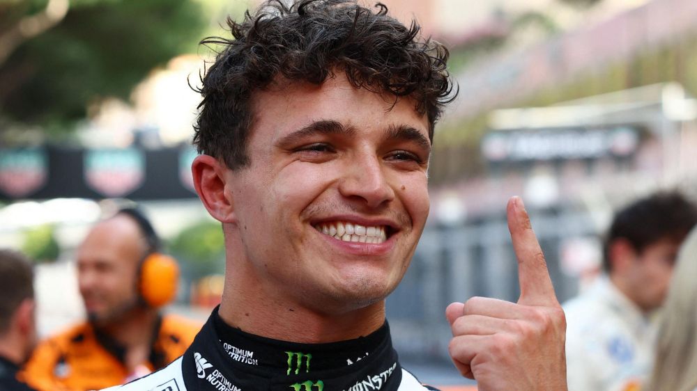 Lando Norris smiling and putting up the number 1 with his finger 