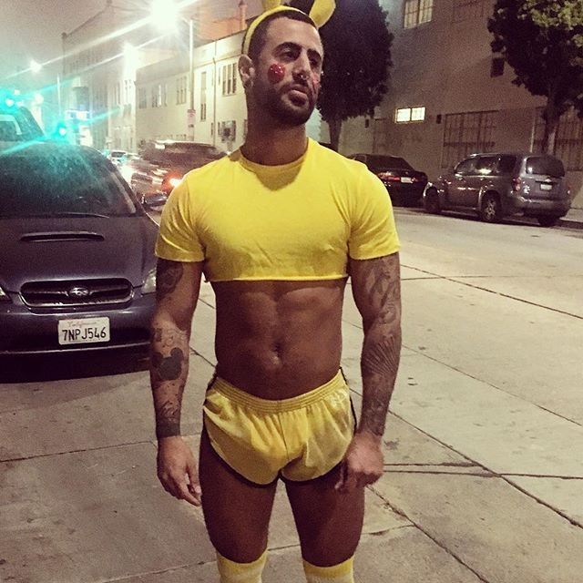 Fit man wearing a very cropped yellow shirt, short yellow shorts, long yellow socks, yellow bunny ears, with red circles on his cheeks. Slutty Pikachu 